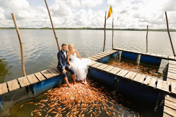 Νύφη και ο γαμπρός κάθεται με τα πόδια τους σε νερό — Φωτογραφία Αρχείου
