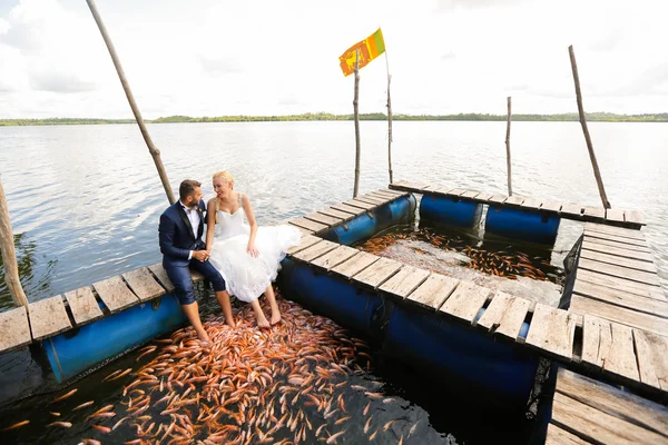 Sposa e sposo seduti con i piedi in acqua — Foto Stock