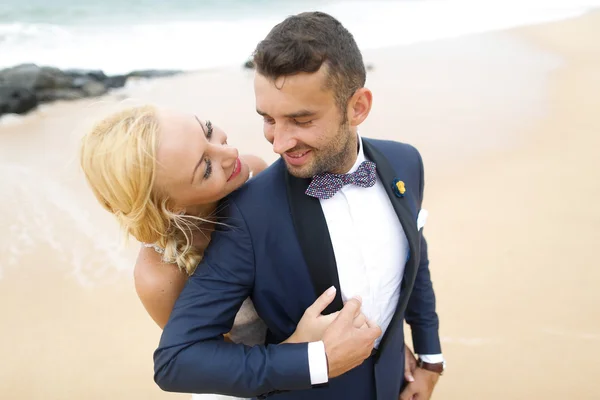 Brud och brudgum poserar på stranden — Stockfoto