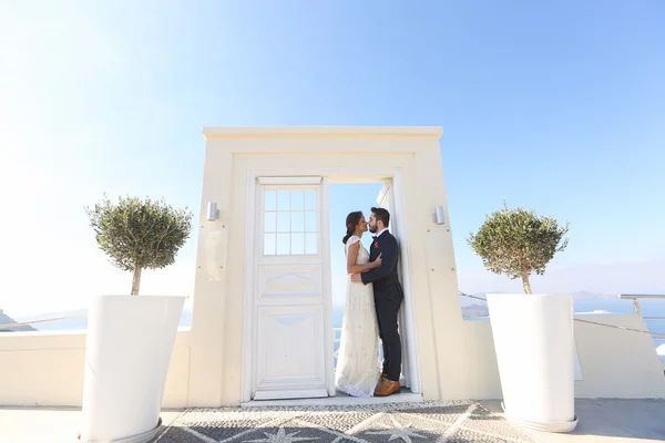 Noiva e noivo beijando perto da porta branca — Fotografia de Stock