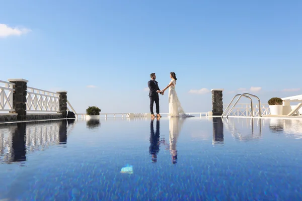 Bruid en bruidegom hand in hand in de buurt van het zwembad — Stockfoto
