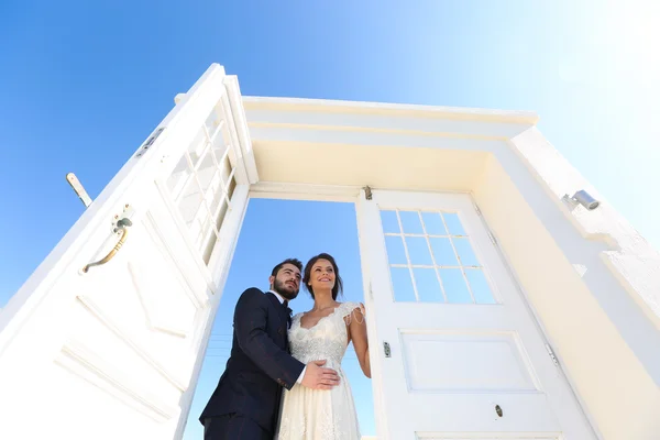 Bruid en bruidegom stairing via een open deur — Stockfoto