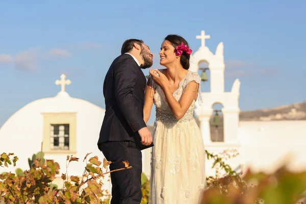 Bruid en bruidegom poseren in de buurt van een witte kerk — Stockfoto