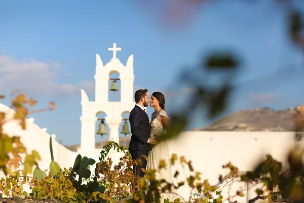 Novia y novio posando cerca de una iglesia blanca —  Fotos de Stock