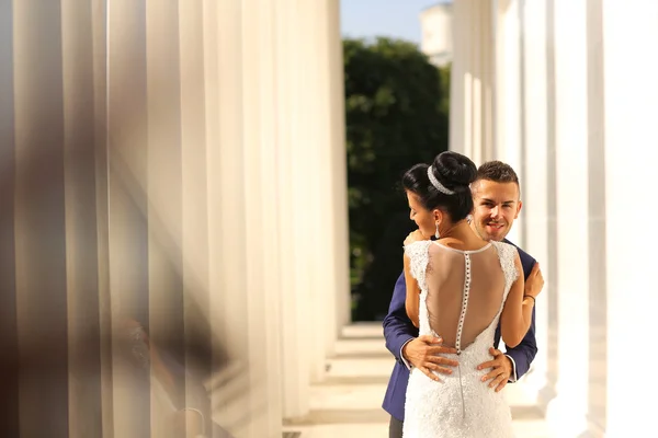 Bella coppia di sposi che abbraccia vicino a colonne — Foto Stock