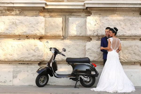 Hermosa pareja nupcial abrazando cerca de scooter —  Fotos de Stock