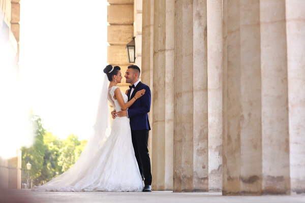 Beautiful bridal couple embracing near columns