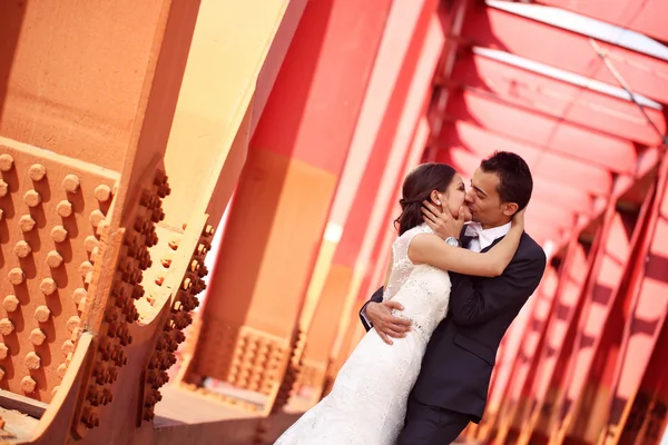 Novia y novio celebrando en un puente rojo — Foto de Stock