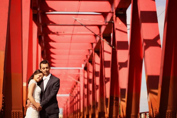 Bride and groom celebrating on a red bridge — Stock Photo, Image