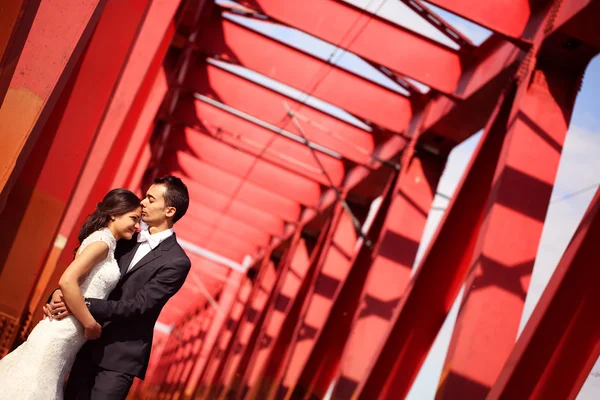 Noiva e noivo celebrando em uma ponte vermelha — Fotografia de Stock