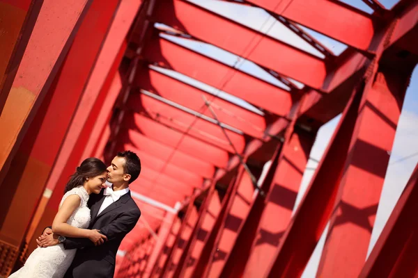 Mariée et marié célébrant sur un pont rouge — Photo