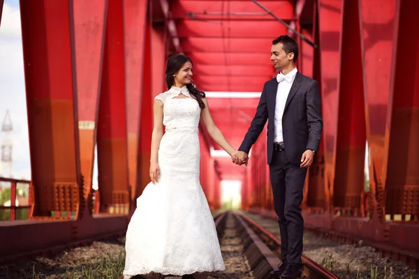 Bruid en bruidegom vieren op een rode brug — Stockfoto