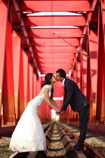 Bride and groom celebrating on a red bridge — Stock Photo, Image