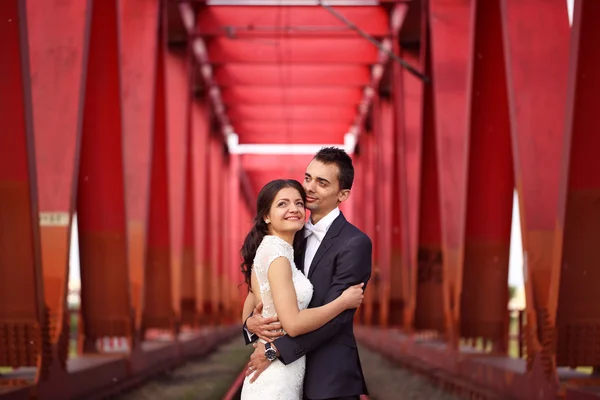 Novia y novio celebrando en un puente rojo — Foto de Stock