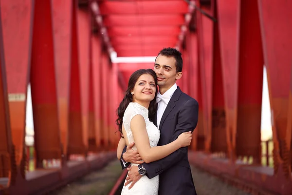 Bruid en bruidegom vieren op een rode brug — Stockfoto