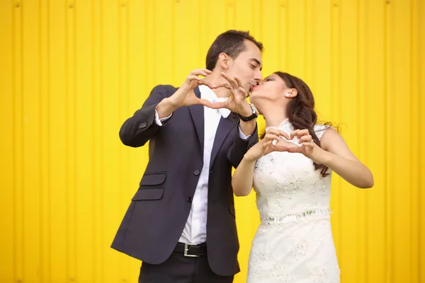 Bride and groom making heart sign — Stock Photo, Image