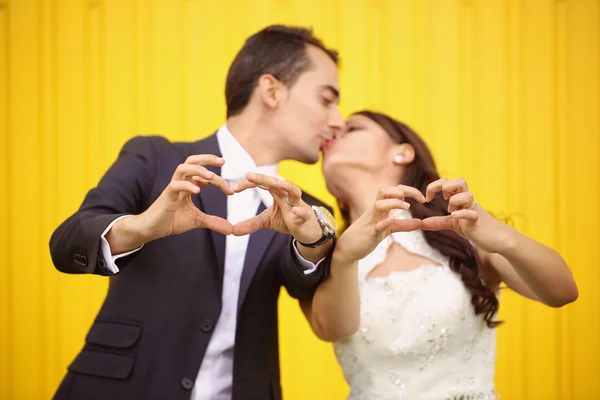 Bride and groom making heart sign — Stock Photo, Image