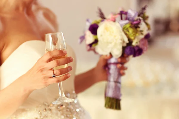 Невеста держит свадебный букет и бокал шампанского — стоковое фото