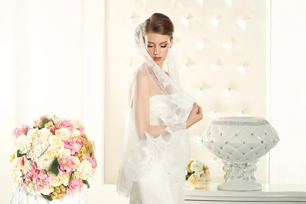 Wunderschöne Braut in einem weißen Raum, posiert — Stockfoto