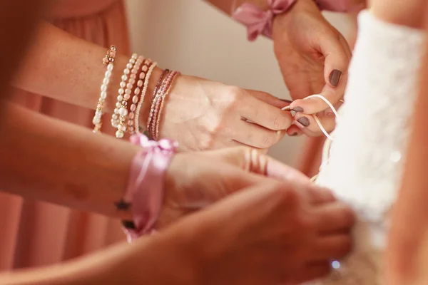 Brides maid helps bride dress in wedding dress for wedding day