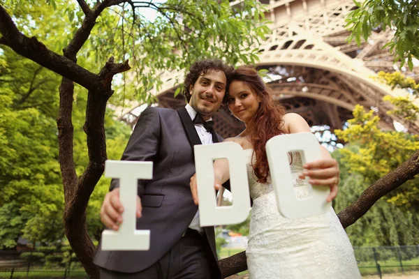 Brud og brudgom holder jeg gør bogstaver i deres hånd nær Eiffeltårnet - Stock-foto
