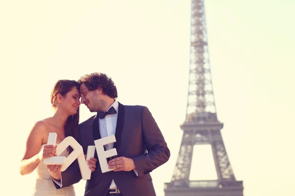 Mariée et marié tenant des lettres d'AMOUR dans leur main à Paris, France — Photo