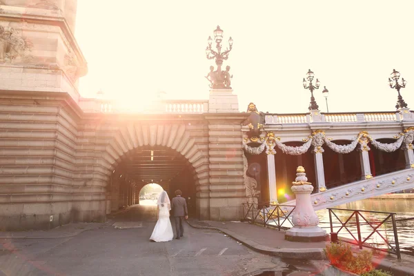 Νύφη και γαμπρός στο φως του ήλιου κοντά σε μια γέφυρα — Φωτογραφία Αρχείου