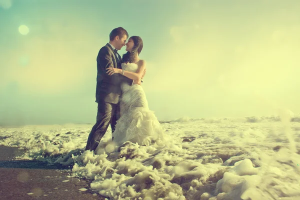 Bruid en bruidegom knuffelen in de zee — Stockfoto