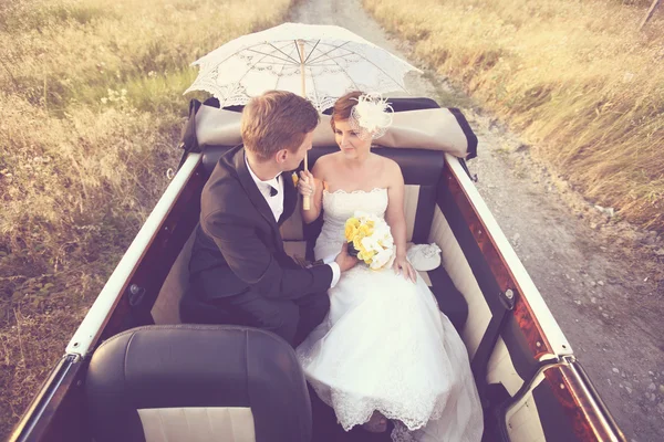 Bride and groom in a vintage car — Stock Photo, Image