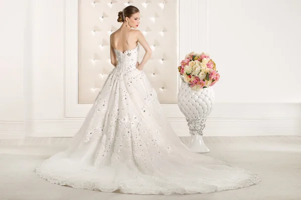 Prachtige bruid met witte jurk met de bloemen boeket — Stockfoto