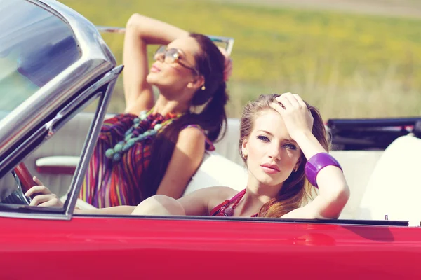 Beautiful ladies with sun glasses riding a vintage retro car — Stock Photo, Image