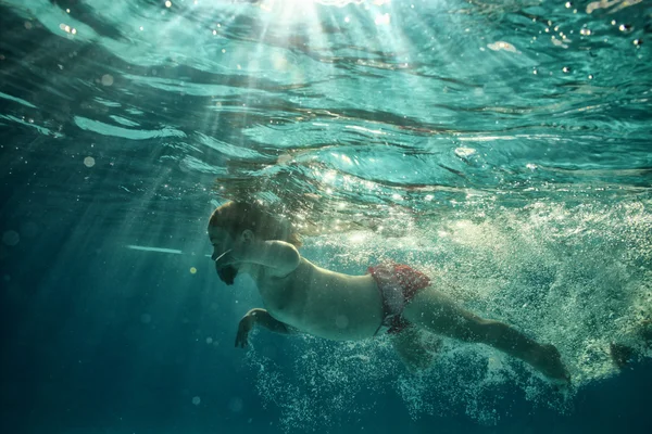 The little girl in the water park swimming underwater and smiling — Stock Photo, Image