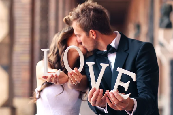 Happy bride and groom holding LOVE letters — Stock Photo, Image