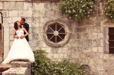 Gelin ve damat taş duvara yakın kucaklayan