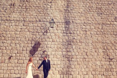 Gelin ve damat yakınındaki duvara elele