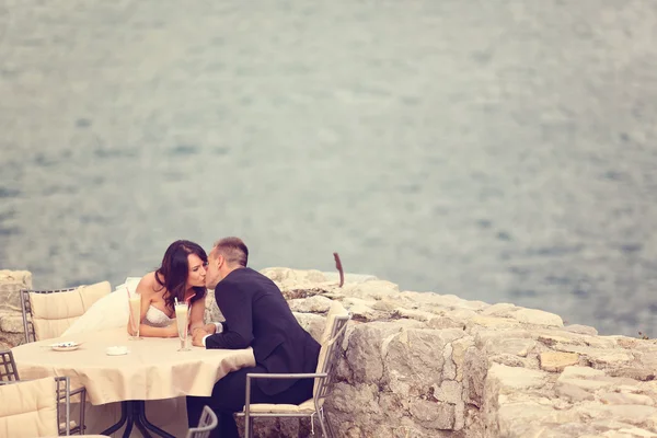 Наречений і наречений цілуються за столом біля моря — стокове фото