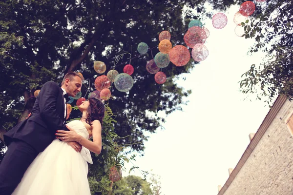 Brudparet kysser under färgglada lampor — Stockfoto