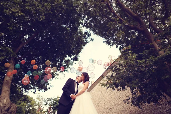 Noiva e noivo beijando sob lâmpadas coloridas — Fotografia de Stock