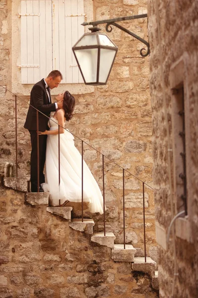 Bride and groom on stairs in old city — Stock Photo, Image