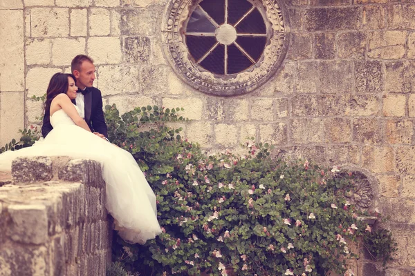 Sposa e sposo abbracciare vicino muro di pietra — Foto Stock