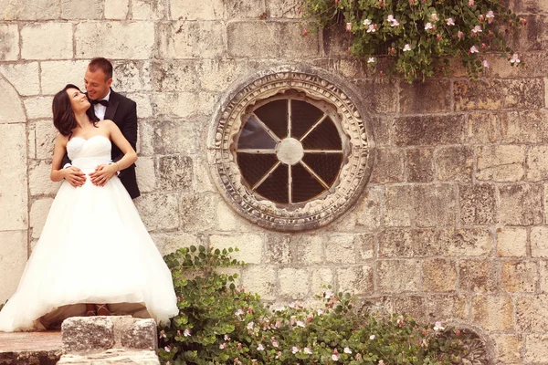 Bride and groom embracing near stone wall — Stock Photo, Image