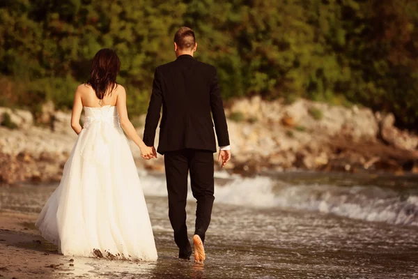 Bride and groom having a walk on the beach — Stock Photo, Image