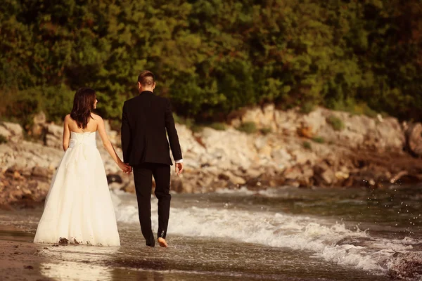 Bride and groom having a walk on the beach — Stock Photo, Image