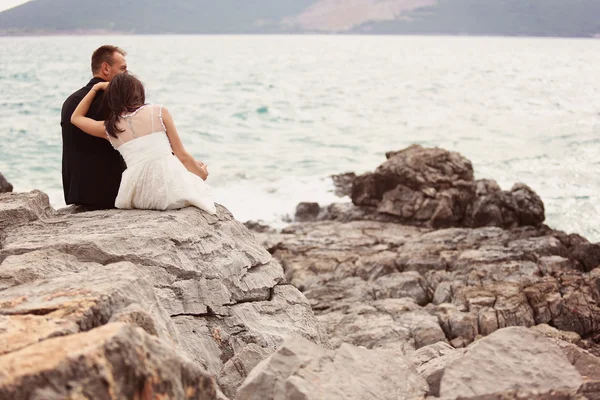 Bride and groom on the rocks at the beach — Stock Photo, Image