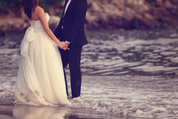 Mariée et marié tenant la main à la plage — Photo