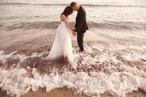 Novia y novio sentados en la playa — Foto de Stock