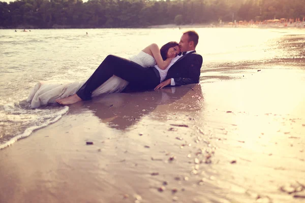 Bride and groom laying on the beach — Stock Photo, Image