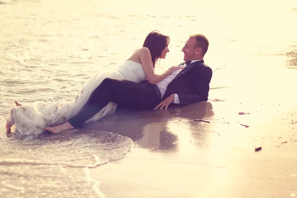 Невеста и жених лежат на пляже — стоковое фото