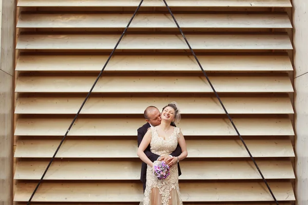 Bride and groom next to stripped wall — Stock Photo, Image