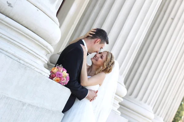 Bruden och brudgummen håller varandra nära kolumner — Stockfoto